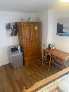 Zimmer mit einem Tisch und einem Holzschrank in der Unterkunft B Homestay in Maidstone
