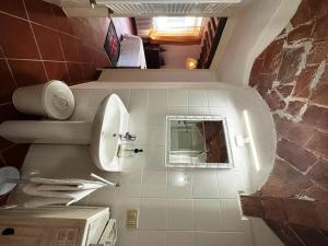 un bagno con lavandino, WC e specchio di Casa del Glicine - Appartamento in palazzo storico a Pugnano Altre 26 foto
