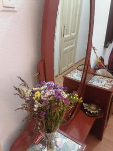 een vaas met bloemen op een tafel voor een spiegel bij Apartman Katedrala in Sarajevo