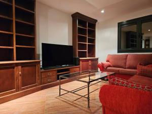 a living room with a tv and a red couch at Mirador La Jirafa - 638A in Oviedo