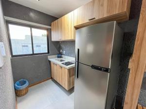 a kitchen with a stainless steel refrigerator and a window at Excelente condomínio com uma belíssima área de lazer próximo à praia do Patacho in Pôrto de Pedras