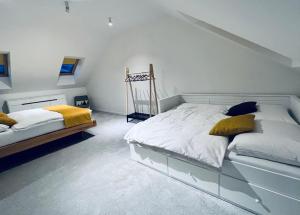 a white bedroom with two beds with yellow pillows at Chalet Furmanski in Stará Lesná