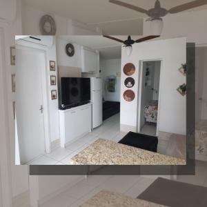 a kitchen and living room with a ceiling fan at Apartamento com piscina, apenas 200 metros do mar in Capão da Canoa