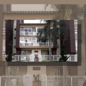 a building with a white fence in front of it at Apartamento com piscina, apenas 200 metros do mar in Capão da Canoa