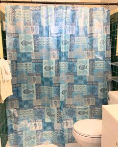 a bathroom with a toilet and a blue shower curtain at The Getaway at Palm Dr in Atlanta