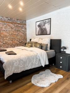 a bedroom with a large bed and a brick wall at FeWo Ottobeurens Schmuckstück: Gemütlich-Stylische Wohnung in Ottobeuren
