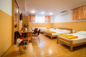 a room with three beds and a table and chairs at Penzion Kovac in Radovljica