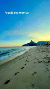a beach with footprints in the sand and the ocean at Lindo apartamento OU quarto em Ipanema a 2min da praia in Rio de Janeiro