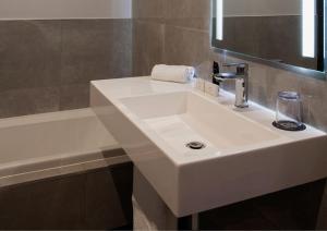 a bathroom with a white sink and a bath tub at Happy Garden Guesthouse in Johannesburg