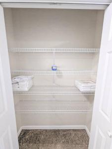 a white closet with white shelves and towels at Luxury & Stylish Townhome, King Beds, W/D, Garage in Schenectady
