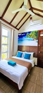 a bedroom with two beds with a painting on the wall at Beach Cottage in Rasdhoo