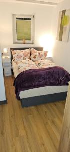 a bed in a bedroom with a wooden floor at Ferienwohnung am Kirchberg Europa-Park Spassbad-Rulantica-Schwarzwald ,Frankreich, in Ettenheim