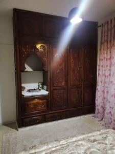 einen Holzschrank mit einem Spiegel im Zimmer in der Unterkunft Superbe appartement en plein médina de Tunis in Tunis