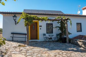 a white house with a yellow door and a table and chairs at Casa do Vale in Marvão