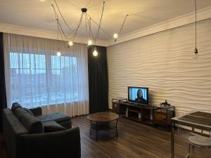 een woonkamer met een bank en een televisie bij Apartament Szarlotka in Łódź