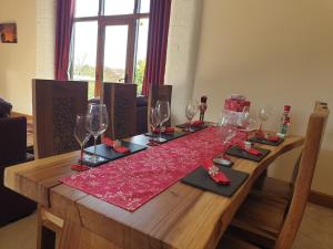 a wooden table with wine glasses and red napkins at The Barn in Landkey