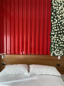un letto di fronte a una parete rossa con fiori di Peaky Hotel a Durrës