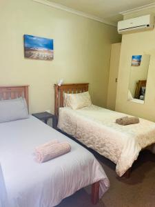 a bedroom with two beds and a mirror at Azalea BnB in Kuruman