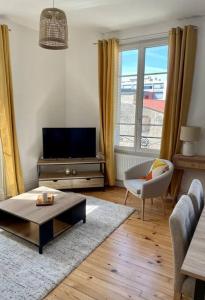 uma sala de estar com uma televisão, um sofá e uma mesa em T3 de charme au centre de Clermont em Clermont-Ferrand