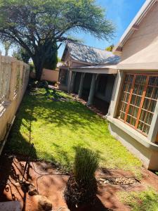 a yard of a house with a fence and a tree at Azalea BnB in Kuruman