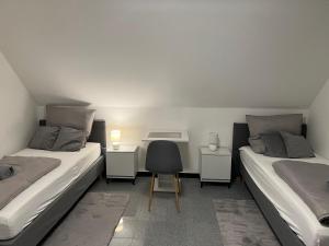 2 łóżka w pokoju z krzesłem i biurkiem w obiekcie Apartment by Harbali w mieście Schüttorf