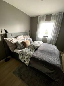1 dormitorio con cama con almohadas y ventana en Hjemmekoselig leilighet med nydelig utsikt en Tromsø