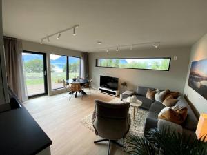 ein Wohnzimmer mit einem Sofa, Stühlen und einem TV in der Unterkunft Hjemmekoselig leilighet med nydelig utsikt in Tromsø
