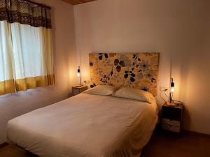 1 dormitorio con cama blanca y cabecero de flores en El Niuet en Pla de l'Ermita
