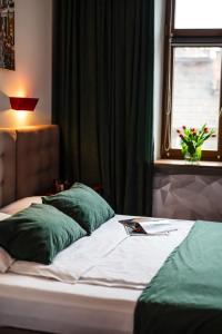 1 cama con almohadas verdes en un dormitorio con ventana en Aparthotel Maargick en Cracovia