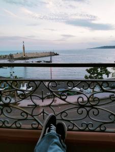 a person sitting on a railing looking at the water at B&B la spiaggetta di Stazzo in Acireale