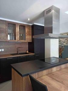 une cuisine avec un comptoir noir et des placards en bois dans l'établissement Magnifique T3 Terrasse, Parking!, aux Rousses