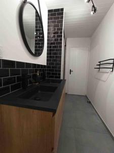 ein Bad mit einem schwarzen Waschbecken und einem Spiegel in der Unterkunft Magnifique T3 Terrasse, Parking! in Les Rousses