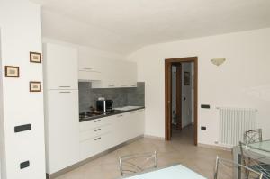 a kitchen with white cabinets and a glass table at B&B Le Fresie in Nuoro