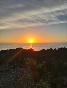 um pôr-do-sol sobre o oceano com o pôr-do-sol em B&B la spiaggetta di Stazzo em Acireale