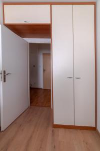 una sala de estar vacía con armarios blancos y suelo de madera. en Strawberry Apartment, en Bratislava
