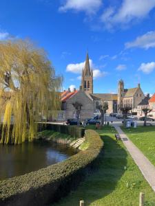 ein Fluss in einer Stadt mit einer Kirche im Hintergrund in der Unterkunft Huyze Ter Vaete in Lo-Reninge