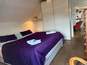 Un dormitorio con una cama morada con toallas. en Skovridergaardens Ferielejligheder en Åbenrå