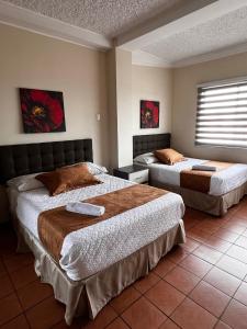 a hotel room with two beds and a window at Hotel Ebenezer in Santo Domingo de los Colorados