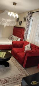 ein Wohnzimmer mit einem roten Sofa und einem Bett in der Unterkunft Soneyhomes in Nairobi