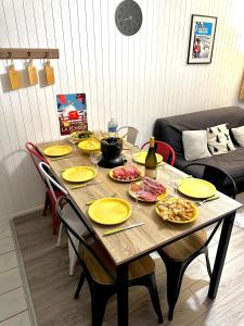 stolik z żółtymi talerzami i butelkę wina w obiekcie Appartement cosy Centre station de Super Besse pour 2 à 6 personnes w mieście Besse-et-Saint-Anastaise +9 zdjęć