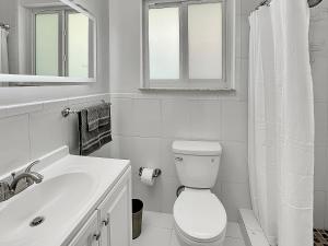 Baño blanco con aseo y lavamanos en Central Studio 17 en Miami