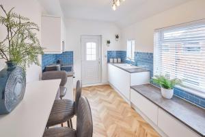 Una cocina con gabinetes blancos y una mesa y sillas. en Marshlands, en Redcar