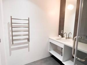 a white bathroom with a sink and a mirror at New Beautiful Modern One Bedroom Apt in Brooklyn at Rem-Casa in Brooklyn