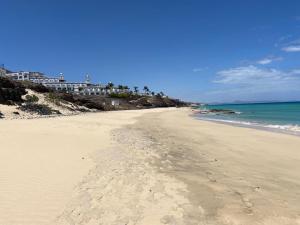 een strand met voetafdrukken in het zand en de oceaan bij Beach Morro Jable Fuerteventura in Morro del Jable