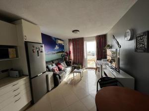 een keuken en een woonkamer met een bank en een koelkast bij Beach Morro Jable Fuerteventura in Morro del Jable