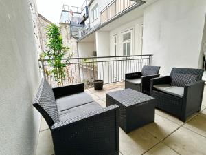100m2 Flat with Balcony near Mariahilferstrasse - Free Parking في فيينا: شرفة مع كراسي وطاولات على شرفة