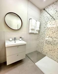 ein Bad mit einem Waschbecken, einem Spiegel und einer Dusche in der Unterkunft morand I Apartments in Salzburg
