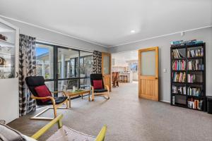 a living room with two chairs and a book shelf at Bootten's Hut in Rotorua