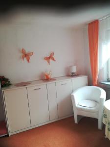 a room with a white cabinet with butterflies on the wall at Gaestehaus jagsttalblick in Langenburg