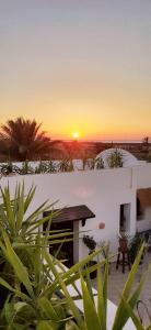 a sunset over a white building with a sunset in the background at Dar Cristina in Houmt Souk